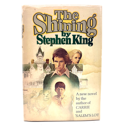 Book cover of 'The Shining' by Stephen King with a man, woman, and child in front of a castle.