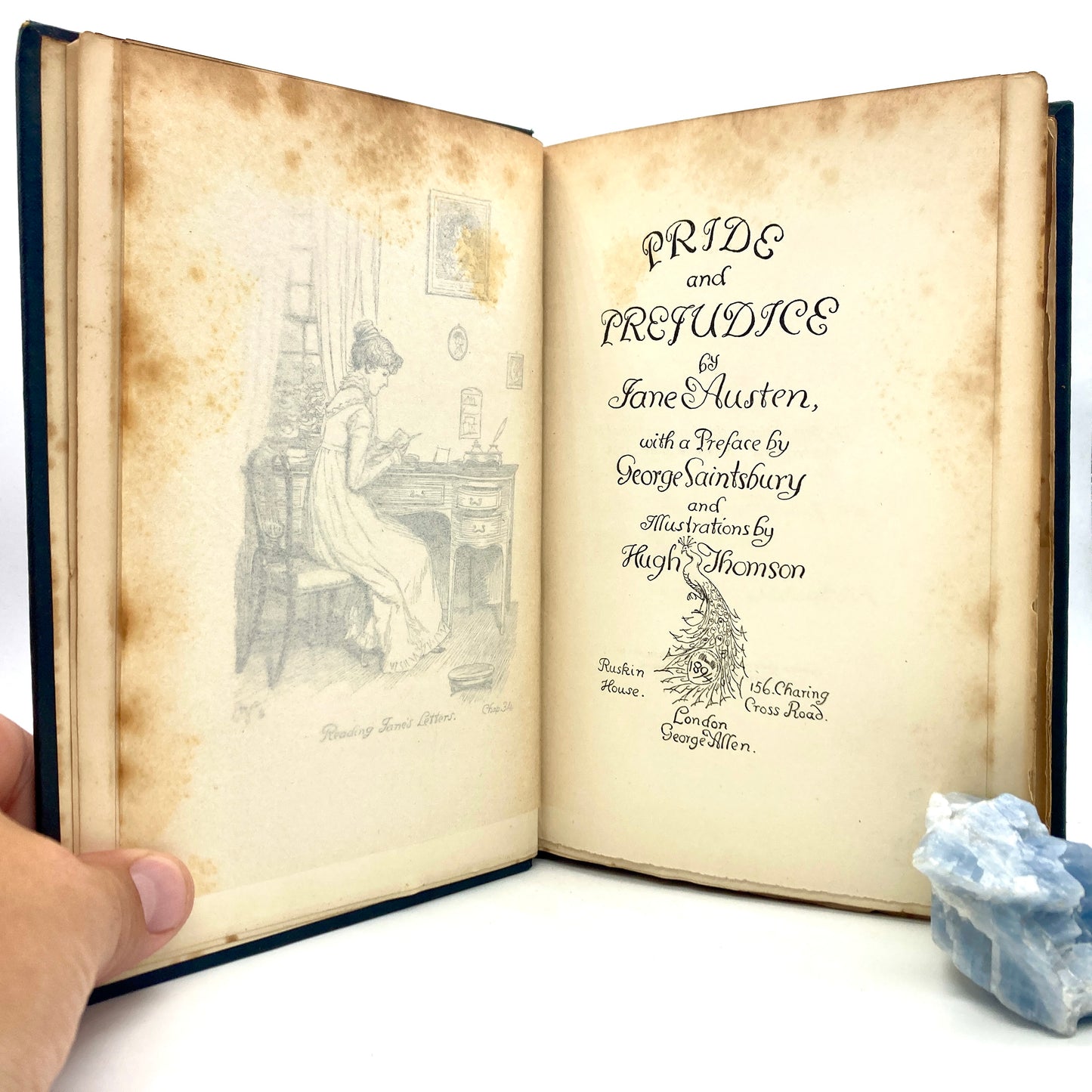 Open book of 'Pride and Prejudice' by Jane Austen with a hand holding it on a white background.